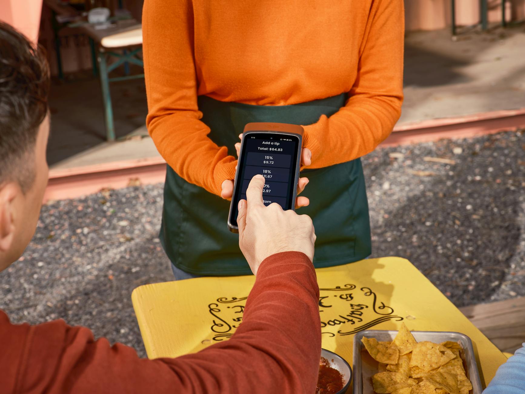 Gość w USA daje napiwek telefonem przy stoliku w restauracji na zewnątrz