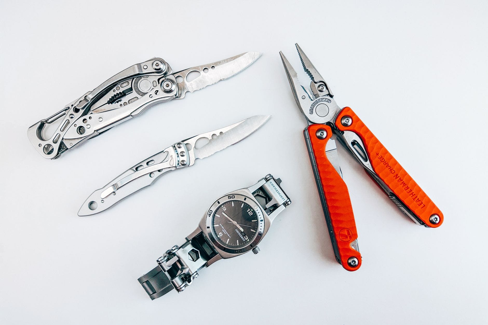 Minimalistyczny zestaw EDC: multitool, scyzoryk i zegarek na białym tle