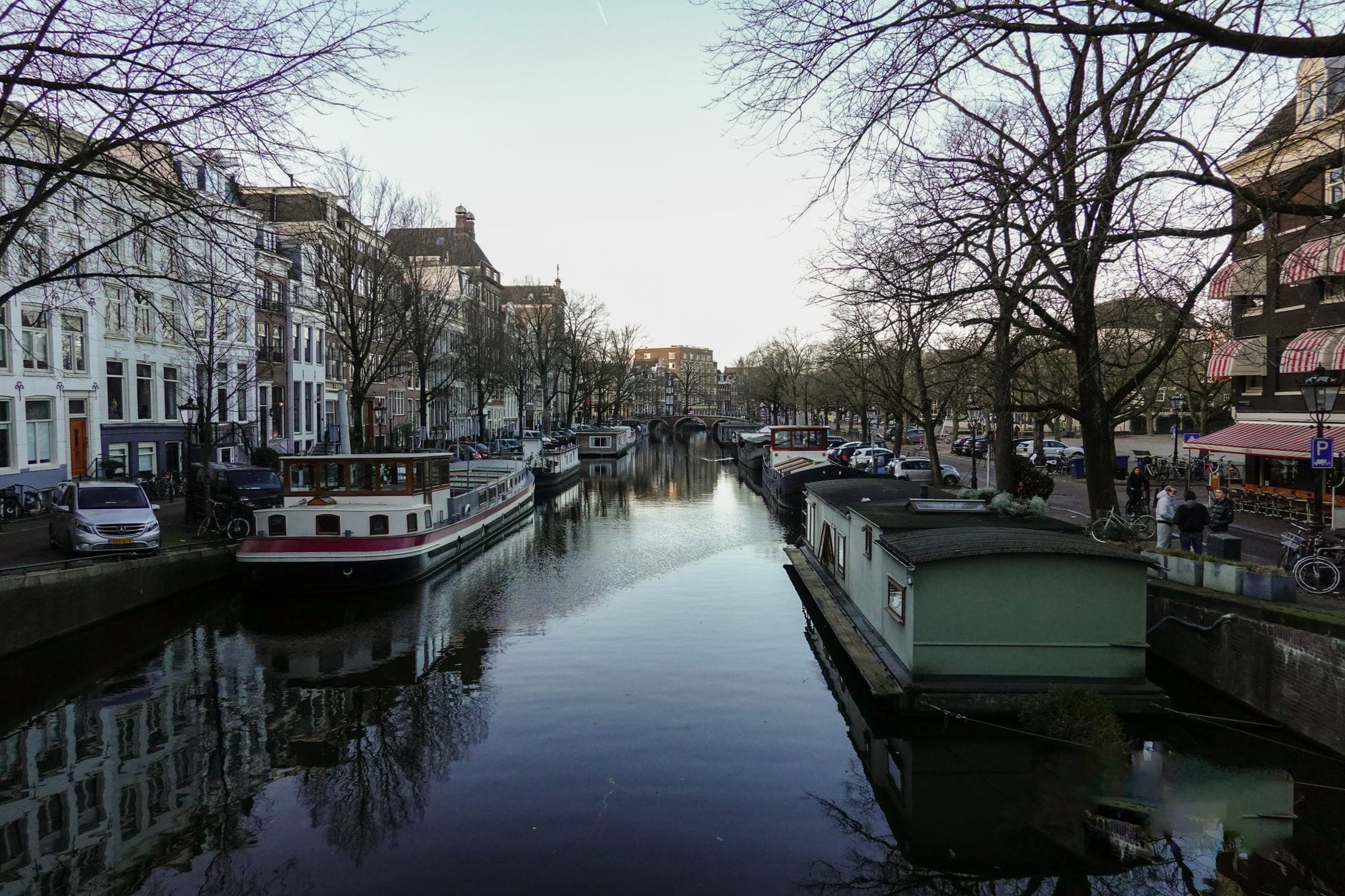 Wieczorny kanał w Amsterdamie z oświetlonymi barkami mieszkalnymi