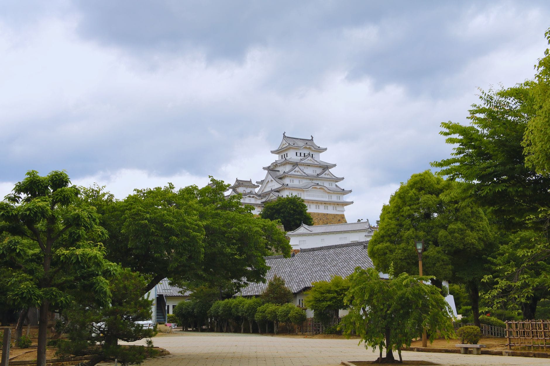 Zamek Himeji w Hyogo otoczony zielonymi drzewami pod pochmurnym niebem