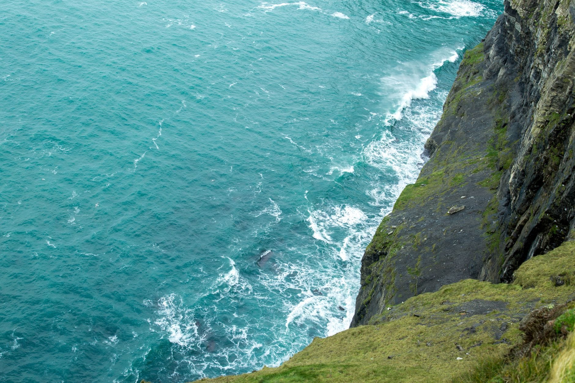 Strome irlandzkie klify nad oceanem z falami rozbijającymi się u podnóża
